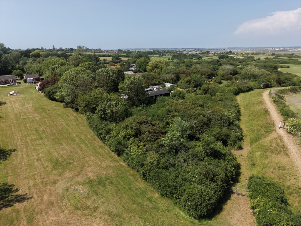 Lot: 82 - 0.88 ACRE FREEHOLD PARCEL OF LAND - Aerial view of overgrown land showing surrounding area
